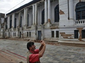 Tourist photographs a damaged building near Basantapur Durbar Square in Kathmandu, Nepal, Monday, June 15, 2015. Nepal on Monday reopened most of the cultural heritage sites that were damaged in a pair of devastating earthquakes, hoping to lure back foreign tourists. (AP Photo/Niranjan Shrestha)