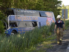 A firefighter attends the scene of an accident where nearly two dozen were injured, four seriously, when a tractor trailer and double-decker bus collided on Highway 401 near Cornwall on Tuesday, June 23, 2015.