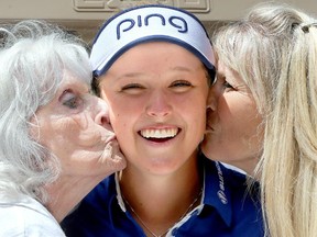 Brooke Henderson laughs as she gets a smooch on the back of a golf cart from her mother, Darlene, and her grandmother, Marlene Moir.