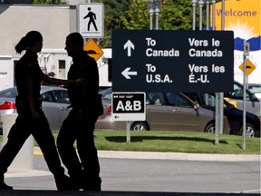 Canadian border guards are silhouetted as they replace each other at an inspection booth at the Douglas border crossing on the Canada-USA border in Surrey, B.C.,in this file shot.