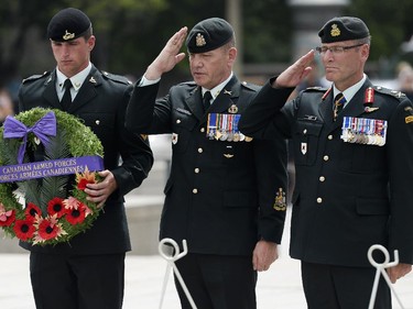 Chief Warrant Officer Alain Guimond (c) and Lieutenant General Marquis Haines (R) salutes during the 62nd anniversary of the Korean War Armistice at War Memorial in Ottawa on Sunday, June 21, 2015.