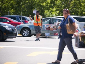 An employee directs cars at the Costco on Cyrville and Innes roads. At peak times, the store brings in off-duty police officers to keep traffic moving.
