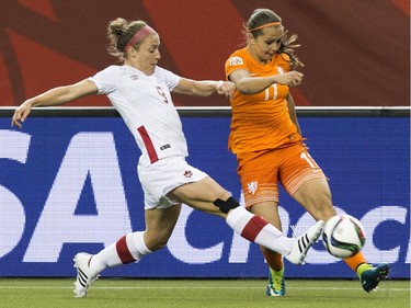 The Netherlands' Lieke Martens (R) crosses despite Canada's Josee Belanger during a 2015 FIFA Women's World Cup Group A football match at the Olympic Stadium in Montreal on June 15, 2015.