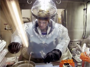 A microbiologist works at the Life Sciences Test Facility at Dugway Proving Ground, Utah. The specialized airtight enclosure is used for hands-on work with anthrax and other deadly agents.
