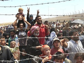 Syrian refugees gather at the Turkish border as they flee intense fighting in northern Syria between Kurdish fighters and Islamic State militants in Akcakale, southeastern Turkey.