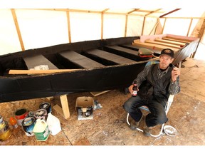 Frank Bertrand takes a break from working on his 22-foot boat — constructed entirely of cardboard, glue and tape — that he hopes will carry 40 people across a small man-made lake at Cedar Shade Campground, near Alfred.