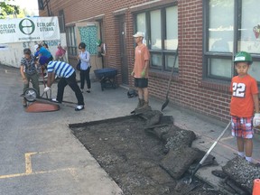 A group of volunteers helps break up the asphalt in front of Ottawa's St. Anthony Catholic School, on June 20 2015.