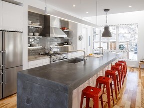 Rob Woyzbun is the family cook and this is his organized empire. A pantry stores all the bottles and boxes and cookbooks, while the main room is serenely organized. A customized concrete island provides more than enough room for cooking and dining. The couple saved money on high-gloss white cabinets and a rustic metal pendant from IKEA and bright red metal stools from Zone and spent on high-end appliances. “We eat almost all of our meals here. If it is more formal, we move to the dining table.”