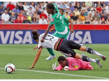 Germany's Celia Sasic (13) flies over Cote d'Ivoire's goalkeeper Dominique Thiamale (16) while defended by Sophie Aguie (21) during the first half of their first match of the FIFA Women's World Cup at TD Place in Ottawa Saturday June 07, 2014.