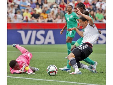 Germany's Celia Sasic (13) has her jersey pulled by Cote d'Ivoire's Sophie Aguie (21) as she challenges goalkeeper Dominique Thiamale (16) during the first half of their first match of the FIFA Women's World Cup at TD Place in Ottawa Saturday June 07, 2014.