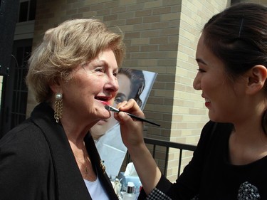 Joan Forbes gets her lipstick touched up by Dior makeup artist Jiawei Li at the annual garden party and fashion show for Cornerstone Housing for Women, held at the official residence of the Irish ambassador on Sunday, June 7, 2015.