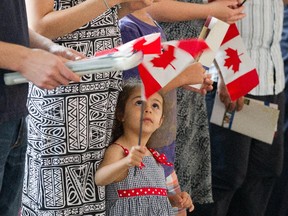 Lucy Galoyan, 3, waves the flag while her mom Araksya Mirzoyan received her citizenship today as 50 new Canadians take the Citizenship Oath during a special Canada Day ceremony held at the Canadian Museum of History in Gatineau, on July 1, 2014.