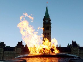 The Centre Block of the Parliament Buildings is shown through the Centennial Flame on Parliament Hill in Ottawa on Sunday, January 25, 2015. Nearly a century of parliamentary tradition is coming to an end with the RCMP poised to take control of security inside the Parliament Buildings.