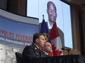 Royal Canadian Mounted Police assistant commissioner James Malizia, left, and Insp. Paul Mellon speak at a press conference at RCMP headquarters in Ottawa about the arrest of a Somali man, Ali Omar Ader (shown on the screen), for his involvement in the kidnapping of Canadian journalist Amanda Lindhout, Friday, June 12, 2015.