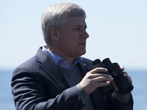 Canadian Prime Minister Stephen Harper uses binoculars to look at ships on the horizon as the HMCS Fredericton sails in the Baltic Sea on Wednesday, June 10, 2015.