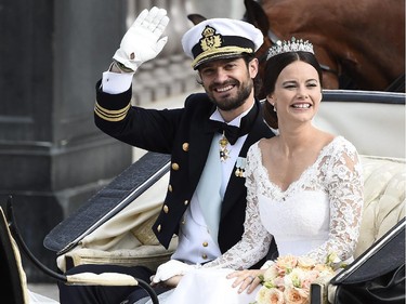 Sofia Hellqvist, right,  and Sweden's Prince Carl Philip wave to the crowds as they ride in a horse-drawn carrige after their wedding at Stockholm Palace on June 13, 2015.