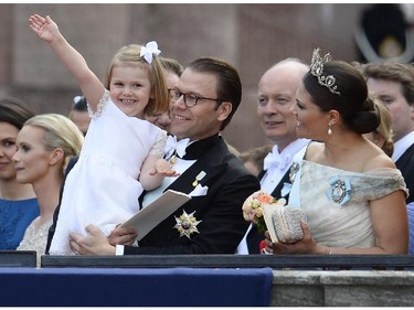 Princess Estelle waves to the crowds held by her father Sweden's Prince Daniel, next to Sweden's Crown Princess Victoria outside the Stockholm Palace after the wedding ceremony of Sweden's Crown Prince Carl Philip and Princess Sofia on June 13, 2015.