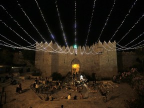 People walk under lights decorating Damascus Gate outside the old city of Jerusalem as Muslims around the world prepared for the announcement of the fasting month of Ramadan. Ramadan is was expected to start on June 17 or 18 depending on the crescent moon.