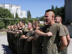 Volunteers from the Azov volunteer battalion read a prayer after a training session in Kiev, Ukraine, Saturday, June 13, 2015. The Azov battalion is primarily made up of volunteers that have been fighting extensively on the frontline in Ukraine's war with pro-Russia separatists.