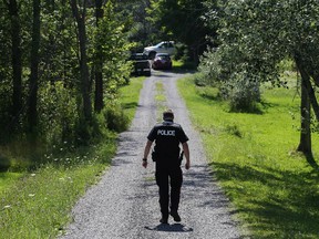 An Ottawa Police officer walks down the lane where a tree fell on someone on Stonecrest Road outside of Ottawa, July 28, 2015.  (Jean Levac/ Ottawa Citizen)
