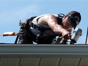 Blake Usher of Remember Me Roofing puts some shingles down in Barrhaven in Ottawa, July 29, 2015. (Jean Levac/ Ottawa Citizen)