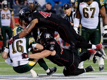 Ottawa Redblacks' Damaso Munoz, top right, and teammate Zach Evans sack Edmonton Eskimos' quarterback James Franklin during first quarter CFL action.