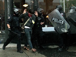 A journalist with visible credentials is arrested by riot police as rain pours down at the conclusion of the G20 Summit June 27, 2010 in Toronto, Canada. Hundreds of people were arrested by police in downtown Toronto during the G20 Summit and many were released prior to the 24-hour limit at which time they had to be charged with a crime.  (Photo by Simon Hayter/Getty Images)
