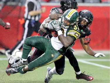 Edmonton's Shakir Bell is dragged down by the Ottawa Redblacks' Brandyn Thompson and Brandon McDonald.