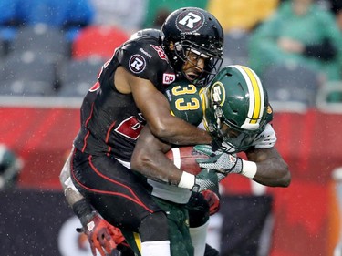 Edmonton's Shakir Bell, right, is dragged down by Ottawa players Brandyn Thompson, left, and Brandon McDonald (hidden).