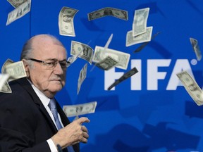 FIFA president Sepp Blatter looks on with fake dollars note flying around him. They were thrown by a protester during a press conference at the football's world body headquarters.