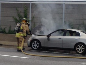 Firefighters extinguish a car fire. The incident blocked Highway 417 Saturday afternoon.