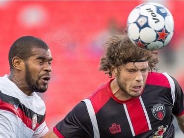 Fury player Tom Heinemann heads the ball while Rauwshan McKenzie, left, moves in to defend.