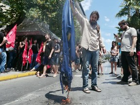 Leftist protesters try to burn a EU flag in front of European commission offices in Athens on July  2, 2015.  Greece's Prime Minister Alexis Tsipras said Thursday his country would remain united after the upcoming referendum, rejecting concerns the vote on bailout measures is splitting the country in two..