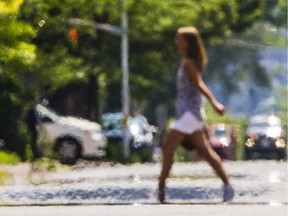 A woman walks across a street in Ottawa with light refracting above the extremely hot pavement during this week's heat wave on Tuesday July 28, 2015.