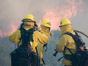 Firefighters watch flames while on structure protection of homes in Oak Hills, Calif., Friday, July 17, 2015. The fire started in the Cajon Pass along Interstate 15, the main highway between Southern California and Las Vegas and quickly chewed through bone-dry brush.