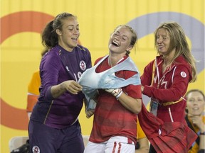 Canada's back-up goaltender, Kailen Sheriden, left, tries to help teammate, forward Janine Beckie, into a singlet before Beckie took over in goal for the team's regular goaltender who received a red card during second half against Equador in women's soccer at the Pan Am Games in Hamilton on Saturday, July 11, 2015.