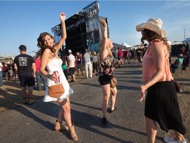 Sam Keyes (L) Daniele Arseneault (C) and Cassie Vincent  (R) dance to Dallas Smith on the Bell Stage as day 8 of the RBC Ottawa Bluesfest gets underway at the Canadian War Museum.