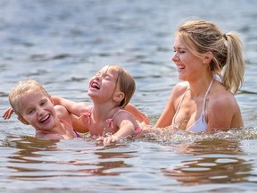 Sydney LaBossiere, 21, caregiver for Alyssa Levesque, 9, left, and her sister Anna Levesque, 6, enjoy a cool dip in Mooney's Bay as the temperature in the region approached the 33C mark.