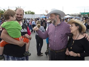 Elijah Day, 3, being held by father Rod Day, left, shyly avoids a fist pump with NDP Leader Thomas Mulcair, second from right, and wife Catherine during a Stampede breakfast in Calgary, Alberta on Saturday.