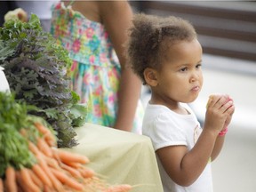 Three-year-old Kalinda Kananura enjoys an apple she got at the Ottawa Farmers Market at the Canadian Museum of Nature, Saturday, July 18, 2015.