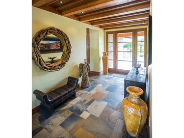 The articulated wood ceiling and slate floor in the main hallway is spectacular and glass doors at the end show off the rear yard and river beyond.