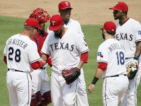 Texas Rangers' Yovani Gallardo turns the ball over to manager Jeff Banister (28) as catcher Bobby Wilson, Adrian Beltre, rear, Elvis Andrus, right rear, and Mitch Moreland (18) stand on the mound in the sixth inning of a baseball game against the Toronto Blue Jays, Thursday, Aug. 27, 2015, in Arlington, Texas.