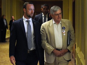 A Conservative supporter, who wouldn't divulge his name, is escorted by private security on contract with the Conservative party, after expressing his frustrations to the media regarding the Duffy questions asked to Conservative  leader Stephen Harper following his announcement in Toronto on Tuesday, August 18, 2015.