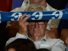 A supporters shades himself from the spot lights as Conservative Leader Stephen Harper delivers a speech during a rally in Vancouver, B.C. on Tuesday, August 11, 2015.