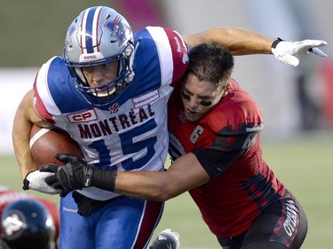 Montreal Alouettes' Samuel Giguere (15) gets tackled by Ottawa Redblacks' Antoine Pruneau (6) during the first half.