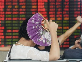 An investor holds a fan as she monitors share prices at a securities firm in Shanghai on August 26, 2015. Shanghai stocks closed down 1.27 percent in volatile trading on August 26, extending days of falls despite a central bank interest rate cut aimed at boosting the flagging economy and slumping shares, dealers said.