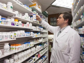 Pharmacist Denis Boissinot checks a bottle on a shelf at his pharmacy on March 8, 2012 in Quebec City.