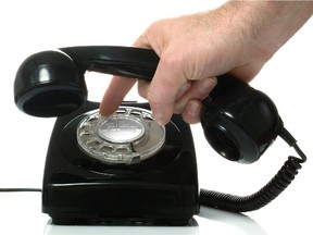 Dialing a number on an old black retro phone.