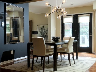 The kitchen table was the starting point for the project, and one of the few pieces of furniture that stayed. Tait paired it with a funky Atom chandelier from Zone and a foxed glass mirror from West Elm, set against a striking black wall.