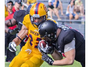 A Carleton Raven leans into a tackle on Queen's Doug Corby at Kingston's Richardson Stadium on Sunday, Aug. 30, 2015.